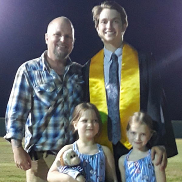 dad with son in graduation gown and two younger daughters